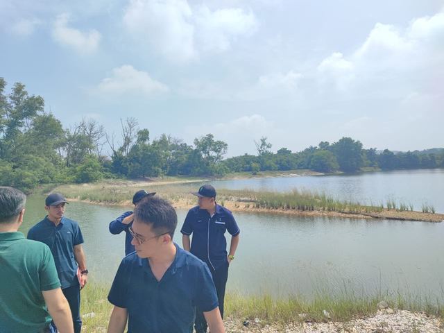 The team on the shoreline, with the lake and grassy banks behind